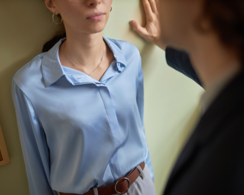 A woman being cornered against a wall by a man.